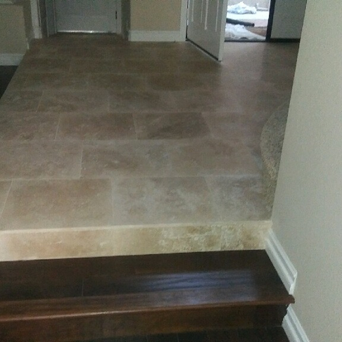 hardwood staircase leading to a tiled hallway